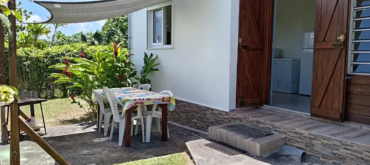 Terrasse extérieure avec table et jardin de Villa Le Gommier au Moule